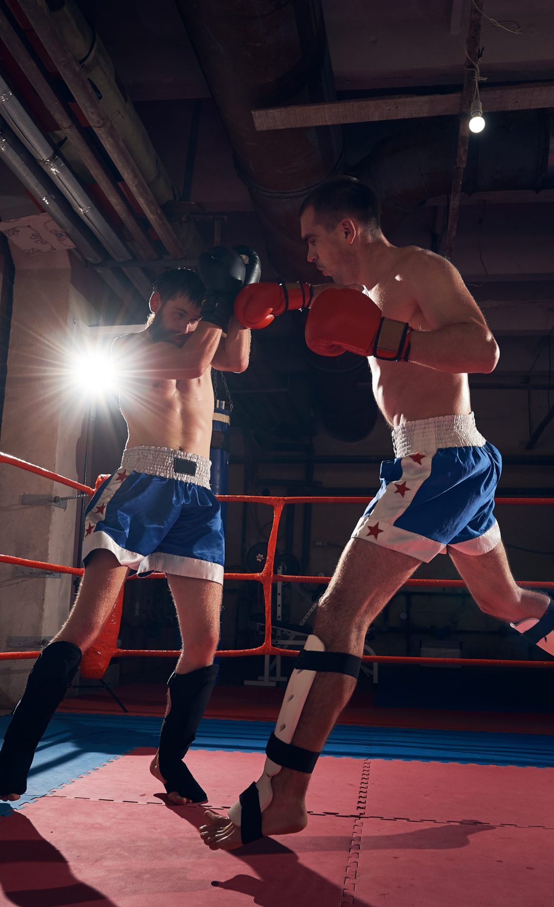 Two professional sportsmen boxers training kickboxing in the ring at the sport club