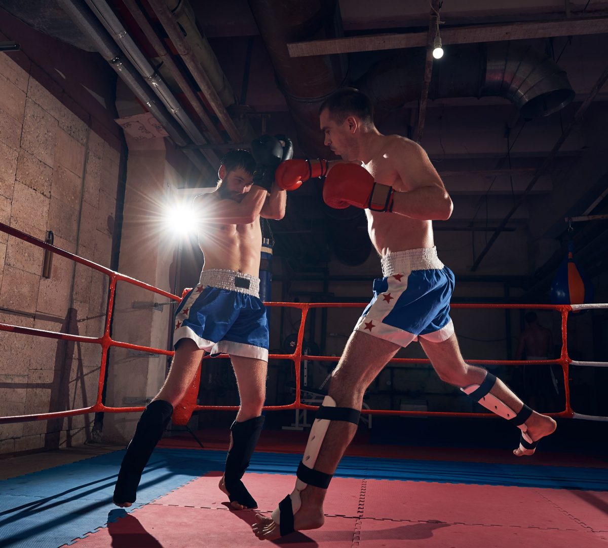 Two professional sportsmen boxers training kickboxing in the ring at the sport club