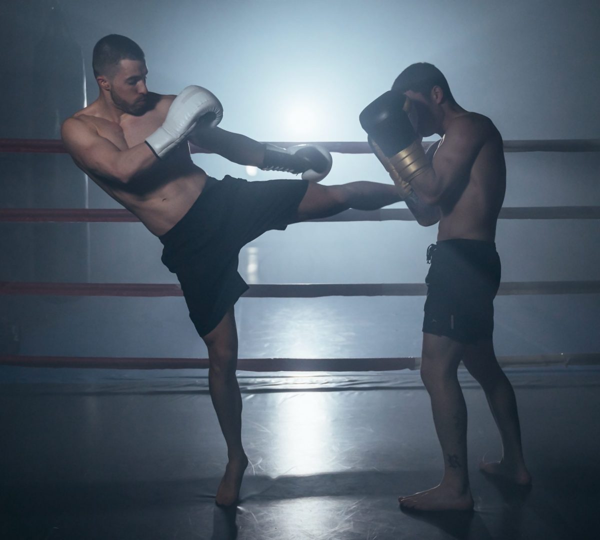 Two shirtless muscular man fighting Kick boxing combat in boxing ring. High quality photo