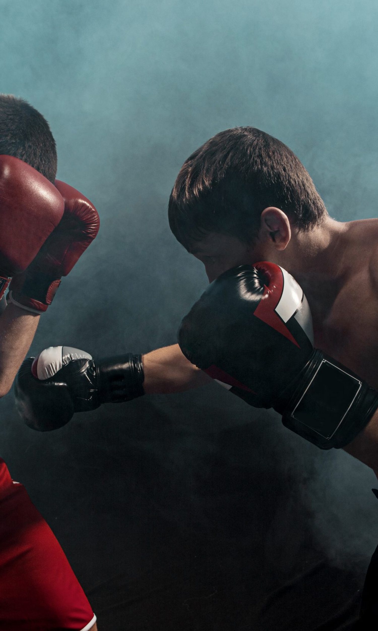 Two professional boxer boxing on black smoky studio background.